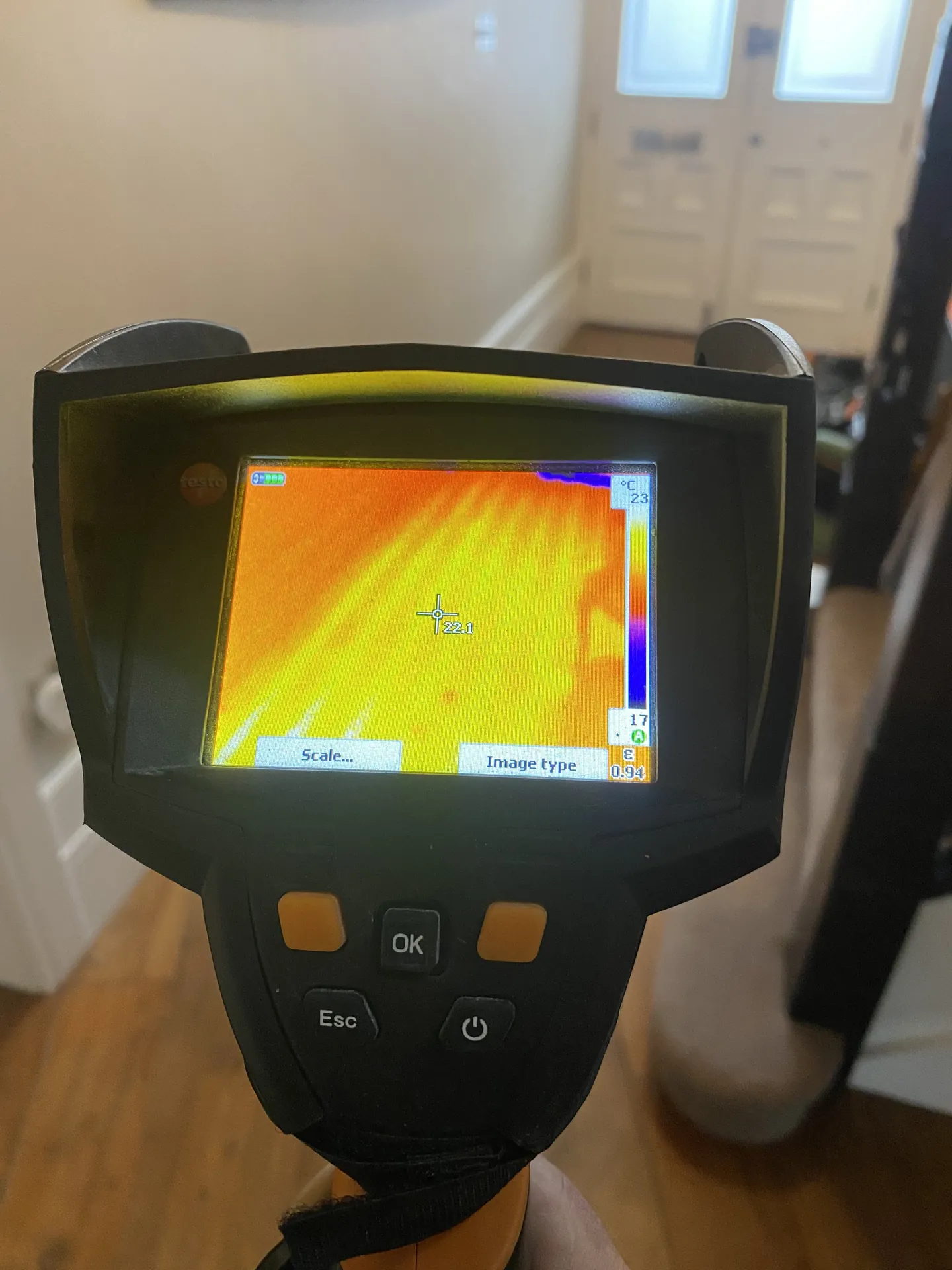 Thermal camera held over a floor with the underfloor heating pipes showing in orange